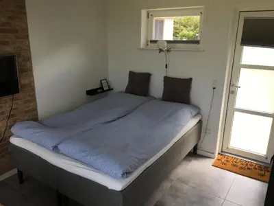 a bedroom with a bed with a blue blanket at Casa Uno North - Nice appartement for two with sea view in Farsø