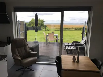 a living room with a sliding glass door to a patio at Casa Uno North - Nice appartement for two with sea view in Farsø