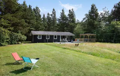 two chairs sitting in the grass in front of a cabin at Nice Home In Højslev With Kitchen in Højslev
