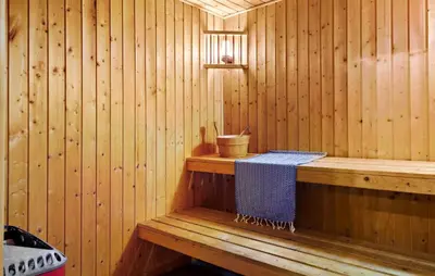 a wooden sauna with a blue towel on a bench at Holiday Home Illeris Farsø Vi in Farsø