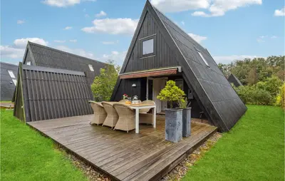 a black house with a table and chairs on a deck at Gorgeous Home In Farsø With Kitchen in Farsø