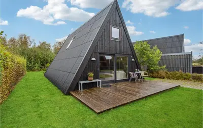 a black clad house with a wooden deck at Gorgeous Home In Farsø With Kitchen in Farsø