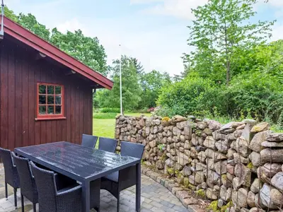 a table and chairs next to a stone wall at 6 person holiday home in Roslev-By Traum in Roslev