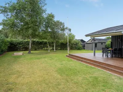 a backyard with a wooden deck and a tree at Holiday Home Ønder - 800m from the sea by Interhome in Blokhus