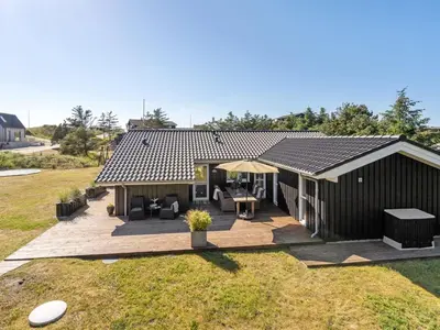 a small house with a deck and a patio at Holiday Home Gun - 450m from the sea by Interhome in Blokhus