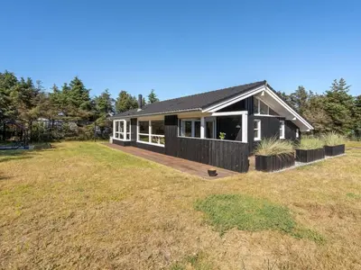 a house with a black roof and a large yard at Holiday Home Gun - 450m from the sea by Interhome in Blokhus