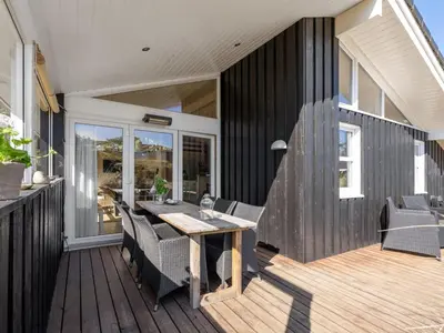 a patio with a table and chairs on a deck at Holiday Home Gun - 450m from the sea by Interhome in Blokhus