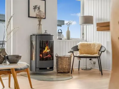 a living room with a fireplace and a chair at Holiday Home Tarvo - 400m from the sea by Interhome in Pandrup