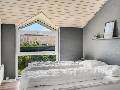 a large white bed in a room with a window at Holiday Home Jenvold - 600m from the sea by Interhome in Torsted