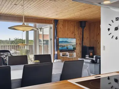 a dining room with a table and a clock on the wall at Holiday Home Wolter - 700m from the sea by Interhome in Harboør