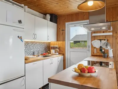 a kitchen with white cabinets and a bowl of fruit on a counter at Holiday Home Wolter - 700m from the sea by Interhome in Harboør