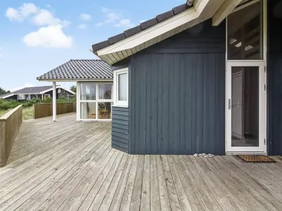 a blue house with a wooden deck at Holiday Home Ilkka - 400m from the sea by Interhome in Torsted
