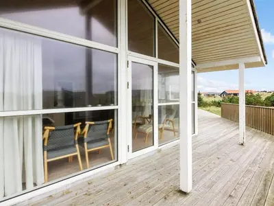 a porch with two chairs and a table and windows at Holiday Home Ilkka - 400m from the sea by Interhome in Torsted