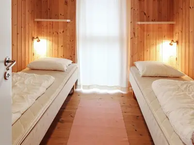 two beds in a room with wooden walls and a window at Holiday Home Ilkka - 400m from the sea by Interhome in Torsted