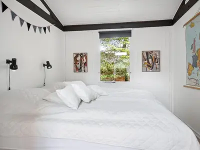 a white bed in a white bedroom with a window at Holiday Home Velika - 1-2km from the sea by Interhome in Thisted