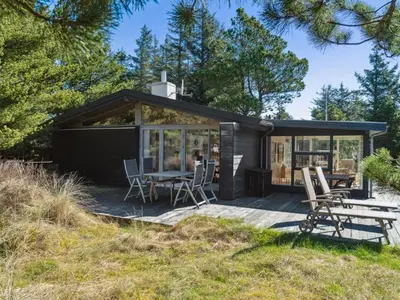 a small black cottage with a table and chairs at Holiday Home Velika - 1-2km from the sea by Interhome in Thisted