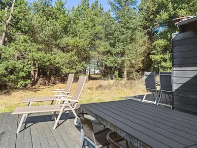 a wooden deck with chairs and a picnic table at Holiday Home Velika - 1-2km from the sea by Interhome in Thisted