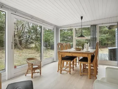 a dining room with a table and chairs and windows at Holiday Home Velika - 1-2km from the sea by Interhome in Thisted