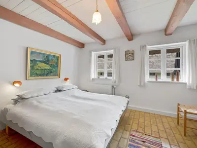 a bedroom with a large bed and two windows at Holiday Home Tatiane - 10km from the sea by Interhome in Bækmarksbro