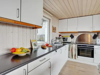 a kitchen with white cabinets and a bowl of fruit on the counter at Holiday Home Ormar - 100m to the fjord by Interhome in Lemvig