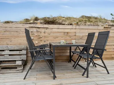 a table and chairs on a deck with the beach at Holiday Home Sulo - 1-4km from the sea by Interhome in Torsted