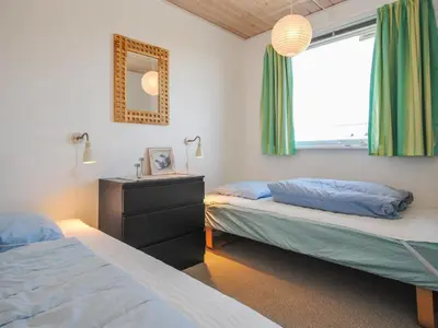 a bedroom with two beds and a window with green curtains at Holiday Home Hilmer - 250m from the sea by Interhome in Torsted