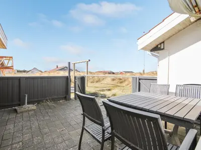 a patio with a wooden table and chairs on a balcony at Holiday Home Hilmer - 250m from the sea by Interhome in Torsted