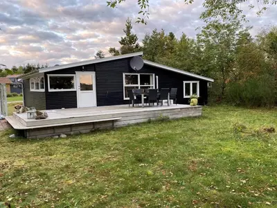a black house with a wooden deck in a yard at Holiday Home Bosi - 100m to the fjord by Interhome in Højslev