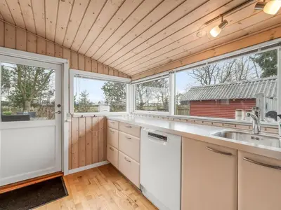 a kitchen with white cabinets and a large window at Holiday Home Bosi - 100m to the fjord by Interhome in Højslev
