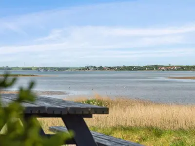 a wooden bench sitting next to a body of water at Holiday Home Swaantje - 150m to the fjord by Interhome in Fur