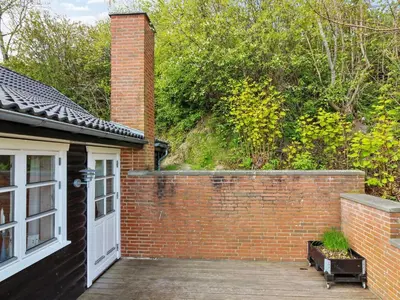 a brick building with a white door and a wooden deck at Holiday Home Sander - 10m to the fjord by Interhome in Roslev