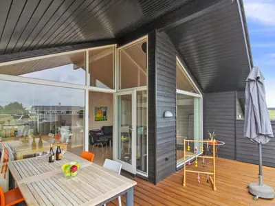 a modern house with a wooden table and a patio at Holiday Home Alma - 500m from the sea by Interhome in Løkken