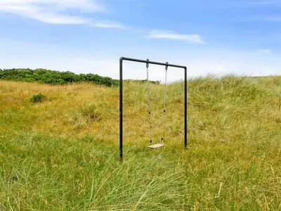 an empty swing set in a field of tall grass at Holiday Home Alma - 500m from the sea by Interhome in Løkken