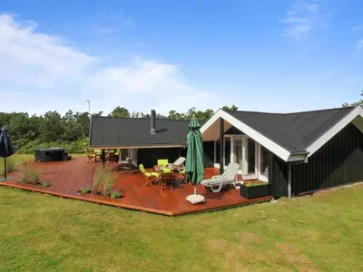 a house with a deck with a grill and a patio at Holiday Home Alban - 700m from the sea by Interhome in Løkken