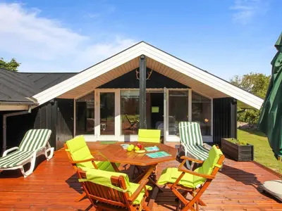 a patio with a wooden table and chairs on a deck at Holiday Home Alban - 700m from the sea by Interhome in Løkken