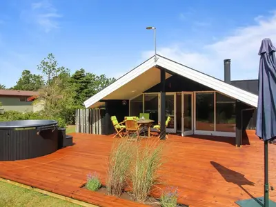 a wooden deck with a table and an umbrella at Holiday Home Alban - 700m from the sea by Interhome in Løkken