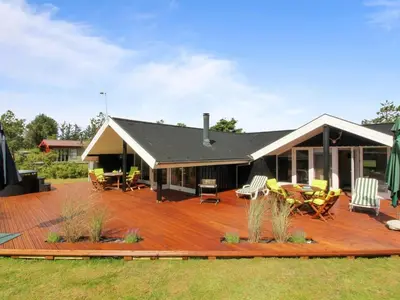 a deck with chairs and tables on a house at Holiday Home Alban - 700m from the sea by Interhome in Løkken