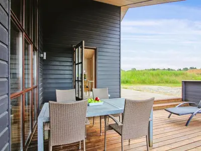 a dining room with a table and chairs on a deck at Holiday Home Ran - 1-5km from the sea by Interhome in Saltum