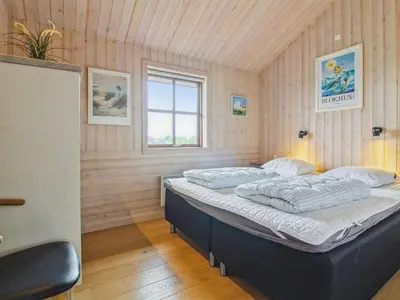 a bedroom with a large bed in a room with wooden walls at Holiday Home Ran - 1-5km from the sea by Interhome in Saltum