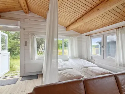 a living room with a couch and windows at Holiday Home Sampo - 400m from the sea by Interhome in Løkken