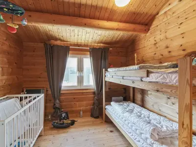 a bedroom with two bunk beds in a log cabin at Holiday Home Sampo - 400m from the sea by Interhome in Løkken