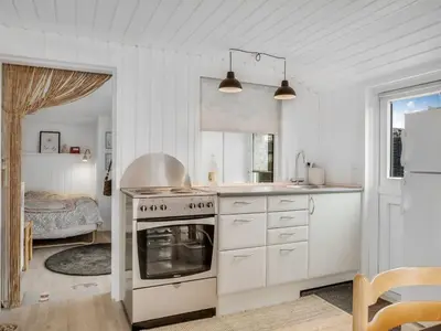 a white kitchen with a stove and a bed at Holiday Home Kielo - 200m to the fjord by Interhome in Løgstør