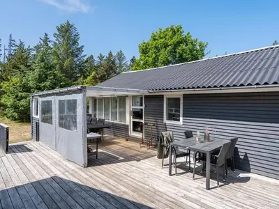 a wooden deck with a table and a house at Holiday Home Aneline - 700m from the sea by Interhome in Saltum