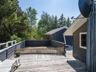 a wooden deck with a fence and a house at Holiday Home Aneline - 700m from the sea by Interhome in Saltum