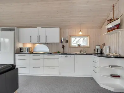 a white kitchen with white cabinets and a window at Holiday Home Aneline - 700m from the sea by Interhome in Saltum