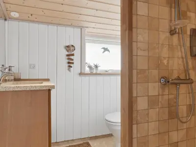a bathroom with a toilet and a window and a shower at Holiday Home Sazdo - 1-1km from the sea by Interhome in Saltum