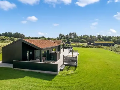 a small black house with a large green field at Holiday Home Egil - 1-5km from the sea by Interhome in Saltum