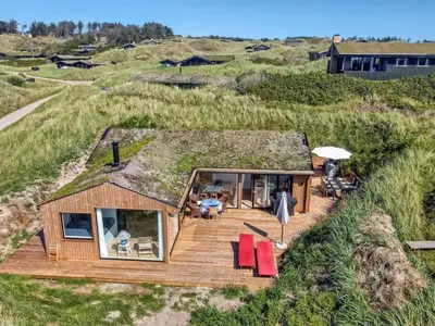 a house with a grass roof with a deck at Holiday Home Hoat - 300m from the sea by Interhome in Saltum