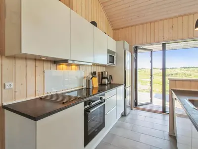 a kitchen with white cabinets and a stove top oven at Holiday Home Ascan - 600m from the sea by Interhome in Løkken