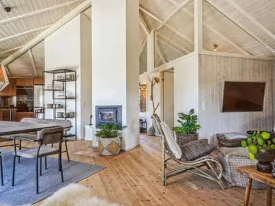 a living room with a table and chairs and a fireplace at Holiday Home Fridgerd - 250m from the sea by Interhome in Blokhus